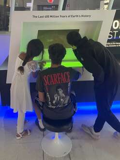 3 children gather around screen in science museum.